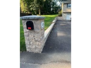 Stone mailbox and paved driveway entrance with clean landscaping