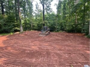 Freshly graded backyard with red soil prepared for lawn installation
