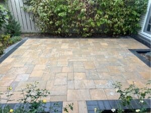 Mixed-color paver patio area beside a privacy fence