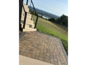 Paver patio landing installed beside an exterior staircase