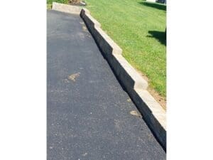 Fresh blacktop driveway edge with clean landscaping border