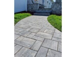 Curved gray paver walkway installed along the side of a home