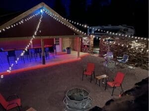 Outdoor patio space with string lights, seating, and fire pit area