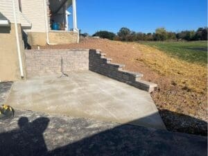 Concrete patio and retaining wall installed beside a home
