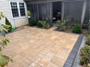 Mixed-color paver patio installed beside a screened porch