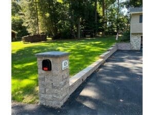 Stone mailbox and paved driveway entrance with clean landscaping