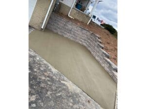 Curved concrete patio and stone retaining wall installed beside a home