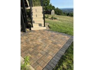 Paver patio landing and steps installed on a sloped backyard