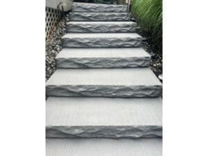 Gray stone steps installed in a landscaped outdoor stairway