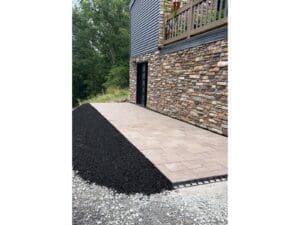 Concrete walkway and stone wall installation beside a raised deck