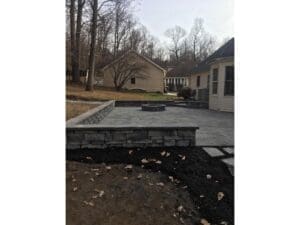 Stone retaining wall and dark mulch bed installed around a home