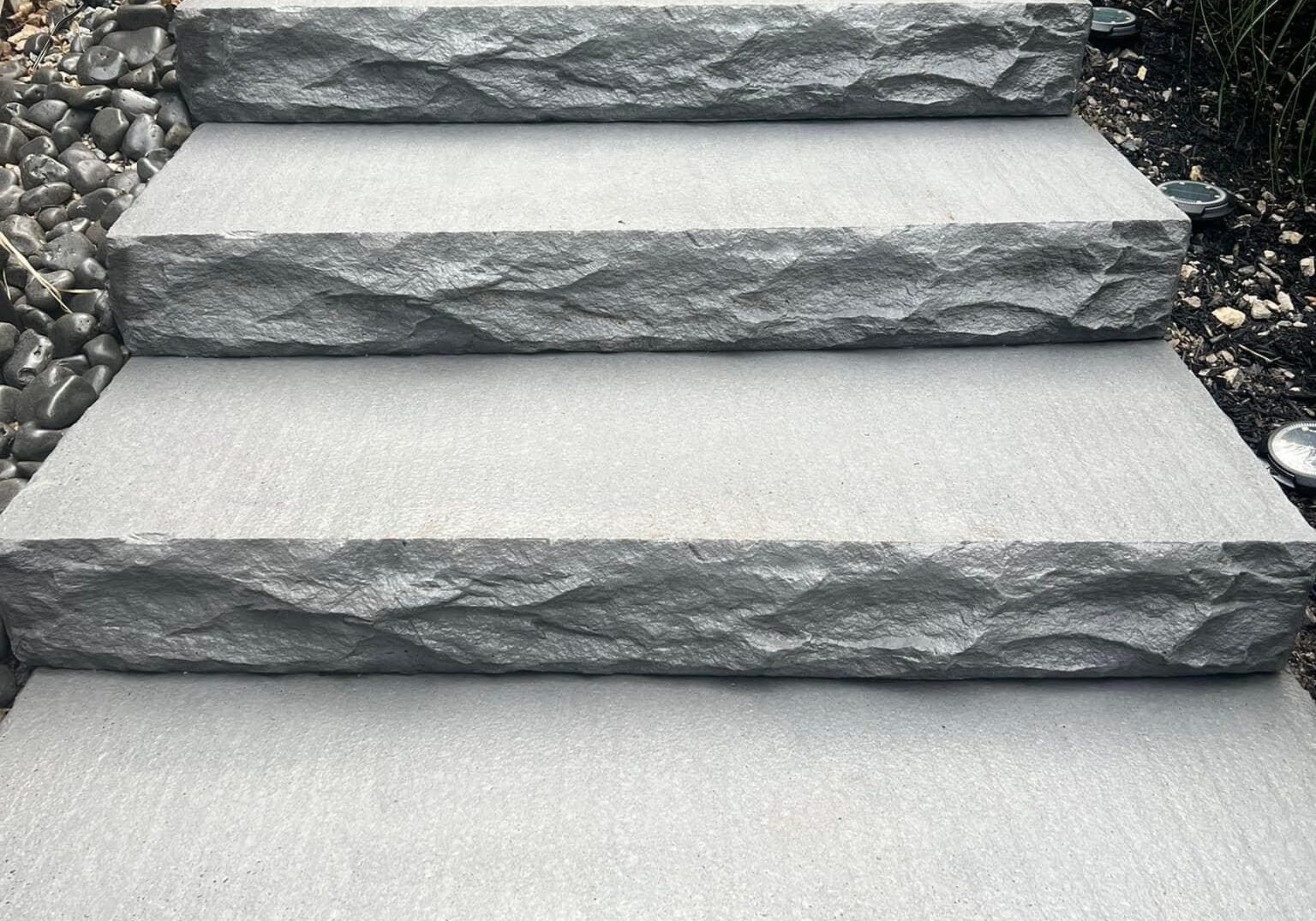 Gray stone outdoor steps installed on a landscaped walkway